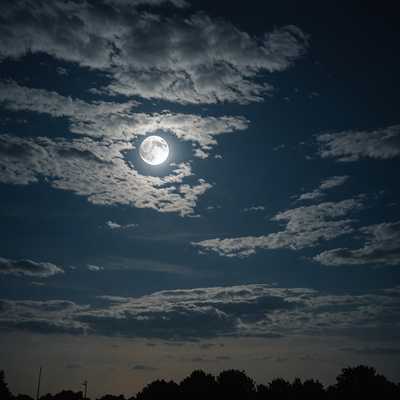 Der Mond, teilweise von Wolken verdeckt, wirft ein blasses, geisterhaftes Licht über die gesamte Szene.