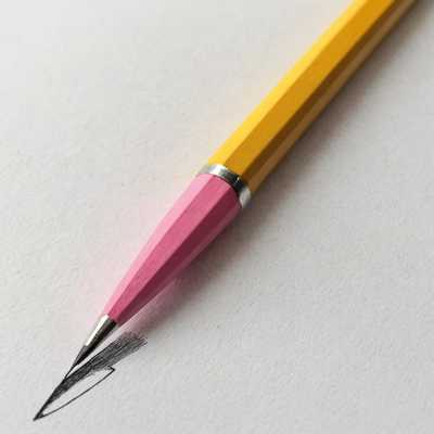 Ein gelber Bleistift mit einer pinken Spitze und einem silbernen Ring liegt schräg auf einem weißen Blatt Papier. Die Spitze des Bleistifts skizziert ein dunkles, schattiertes Dreieck. Das Papier zeigt eine feine Textur und der Bleistift ist von oben rechts nach unten links ausgerichtet.