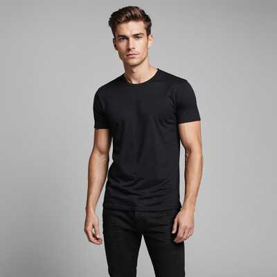 Ein im Studio gut beleuchtetes Fotograf, das einen männlichen Modell zeigt, der modische Kleidung vorführt. Der männliche Modell trägt ein enges schwarzes T-Shirt und dunkle Jeans. Der Hintergrund ist schlicht und unauffällig, wodurch die Kleidung hervorgehoben wird.